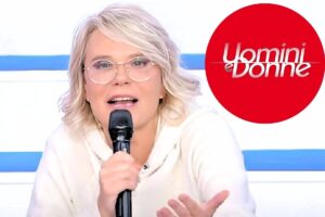 maria de filippi con microfono e logo uomini e donne